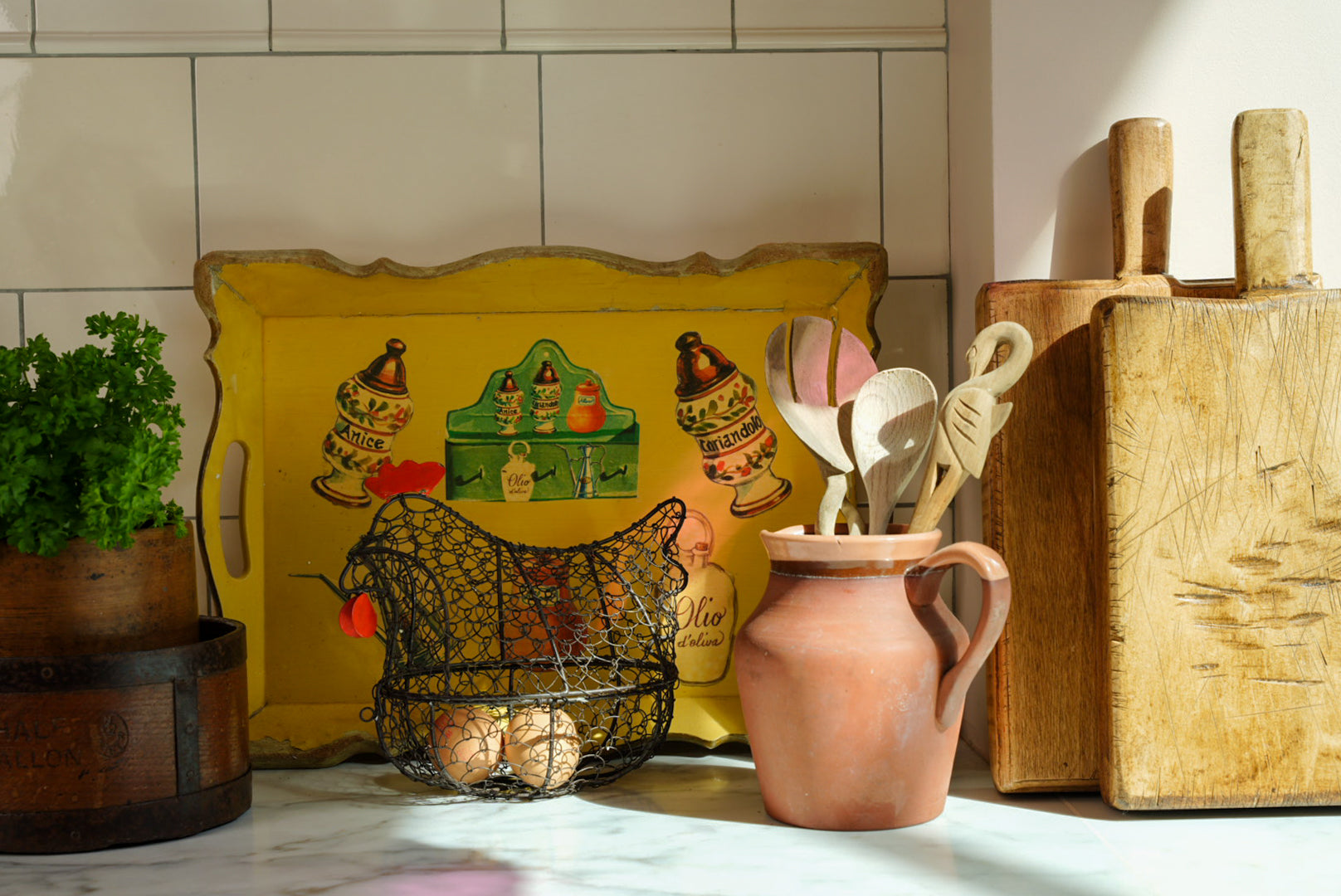 Vintage kitchen shelf styling with antique wooden chopping boards, yellow serving tray, pink ceramic jug and collected home decor.